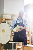 Man examining pottery at kiln in studio