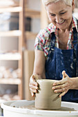 Smiling senior woman using pottery wheel