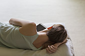 Woman laying on bed with digital tablet