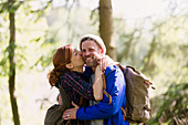 Smiling couple kissing hiking in woods