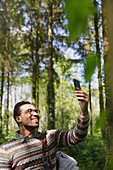 Smiling man taking selfie in sunny woods