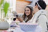 Friends pouring wine at patio lunch table