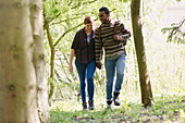 Couple holding hands hiking in woods