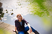 Woman sitting on sunny lakeside dock