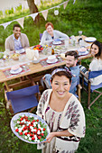 Woman serving Caprese salad to friends