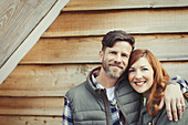 Smiling couple hugging outside cabin