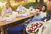 Woman serving Caprese salad to friends