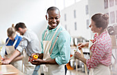 Woman tying man's apron in cooking class