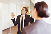 Silly businessman pressing face against glass