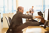 Businessman stretching feet on desk in office