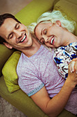 Affectionate laughing couple laying on sofa