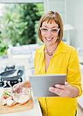 Mature woman using digital tablet and cooking