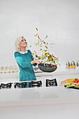 Woman cooking flipping vegetables in skillet