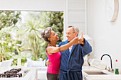 Playful mature couple dancing in kitchen