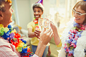 Mature friends in feather boas and leis toasting