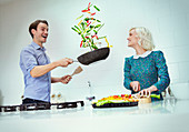 Couple cooking flipping vegetables in skillet