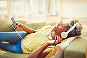 Mature woman listening to music on sofa