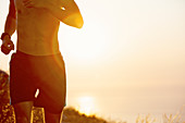 Bare chested man running at sunset