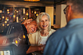 Senior couple laughing and hugging in bar