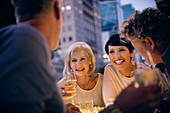 Smiling couples drinking white wine and talking