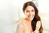 Portrait smiling brunette woman brushing hair