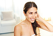 Smiling brunette woman brushing hair