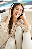 Carefree woman listening to music on sofa