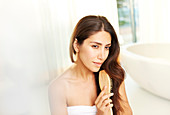 Serene brunette woman brushing hair in bathroom