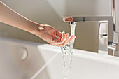 Woman touching water from modern bathtub faucet