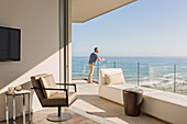 Man enjoying sunny ocean view from luxury balcony