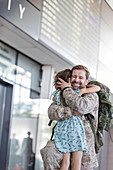 Daughter greeting and hugging soldier father