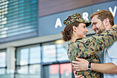 Husband greeting and hugging soldier wife