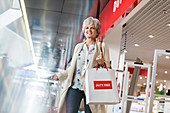 Smiling woman leaving airport duty free shop