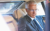 Businessman riding in back seat of town car
