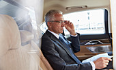 Businessman with paperwork in back seat of car