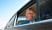 Smiling businessman looking out town car window