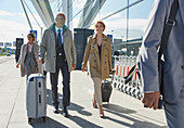 Business people walking pulling suitcases