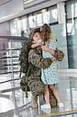 Daughter greeting hugging soldier mother