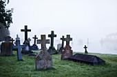 Crosses on gravestones in ethereal foggy cemetery