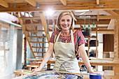 Smiling stained glass artist working in studio