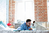 Man playing with Jack Russell Terrier dog on bed