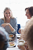Smiling women friends dining at restaurant table