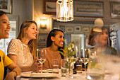 Smiling women friends dining and drinking wine