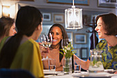 Smiling women friends toasting wine glasses dining