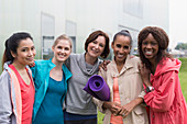 Portrait smiling women friends with yoga mat