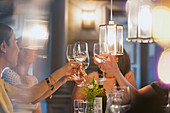 Women friends toasting white wine glasses dining