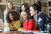 Women friends using laptop at restaurant table