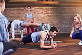 Young man and woman practicing stacked plank pose