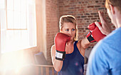 Young female boxer practicing boxing with trainer