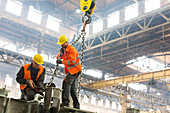 Steel workers fastening crane chain to steel